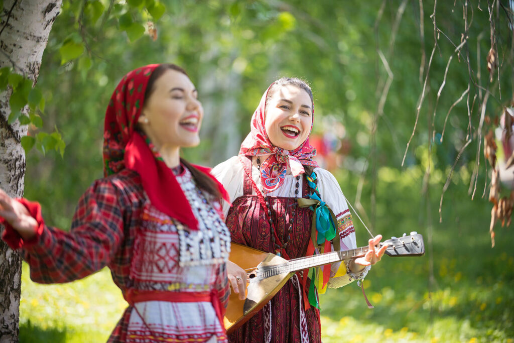 Zwei russische Frauen in traditioneller Tracht, eine spielt Balalaika
